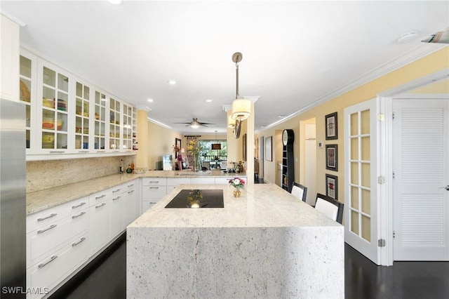 kitchen with a kitchen breakfast bar, kitchen peninsula, black electric cooktop, decorative light fixtures, and white cabinetry