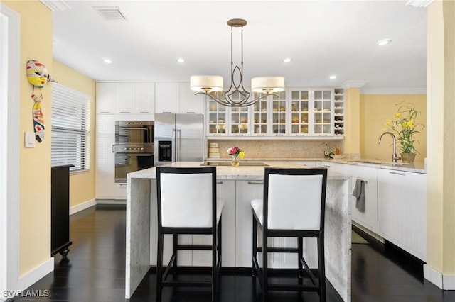 kitchen with white cabinetry, sink, stainless steel refrigerator with ice dispenser, decorative light fixtures, and a kitchen island