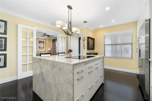 kitchen featuring light stone counters, dark wood-type flooring, white cabinets, a center island, and hanging light fixtures