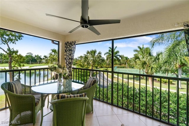 sunroom featuring ceiling fan and a water view