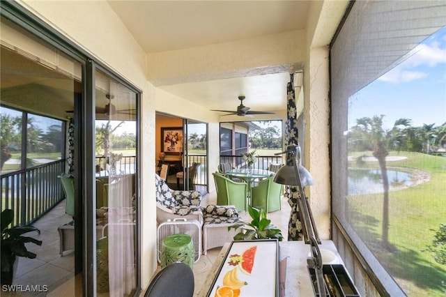 sunroom featuring ceiling fan and a water view