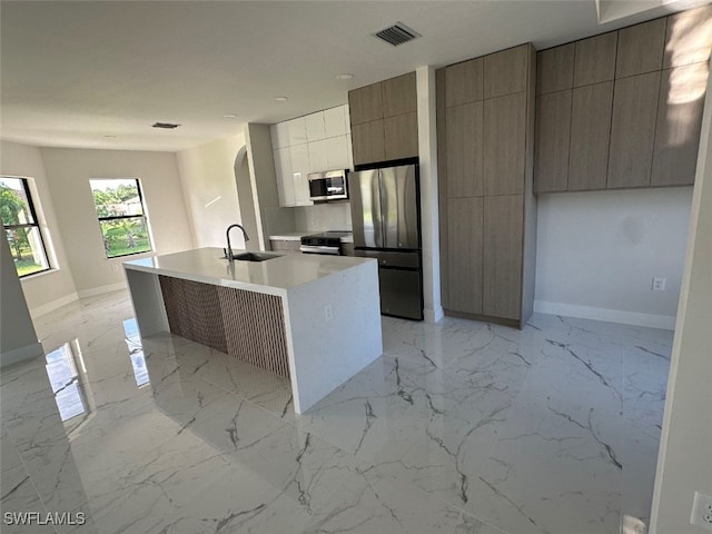 kitchen featuring sink, an island with sink, and appliances with stainless steel finishes