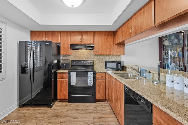 kitchen featuring a tray ceiling, light stone countertops, and black appliances