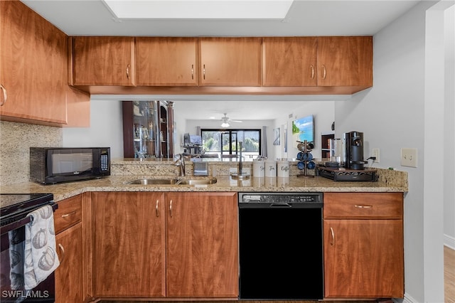 kitchen with light stone countertops, sink, backsplash, and black appliances