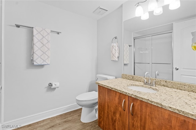 bathroom with hardwood / wood-style flooring, toilet, vanity, and walk in shower