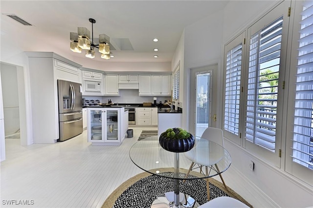 kitchen with decorative light fixtures, a notable chandelier, stove, white microwave, and stainless steel fridge