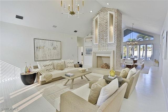 living room featuring high vaulted ceiling, a large fireplace, an inviting chandelier, and light hardwood / wood-style floors