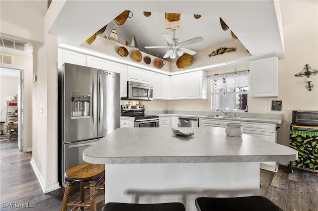 kitchen featuring sink, dark wood-type flooring, a kitchen breakfast bar, white cabinets, and appliances with stainless steel finishes