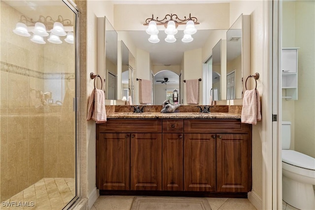 bathroom featuring tile patterned flooring, vanity, an enclosed shower, and toilet