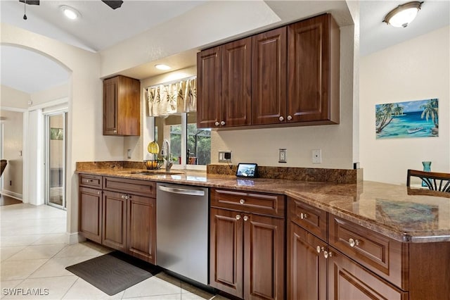 kitchen featuring sink, stainless steel dishwasher, dark stone counters, and light tile patterned flooring