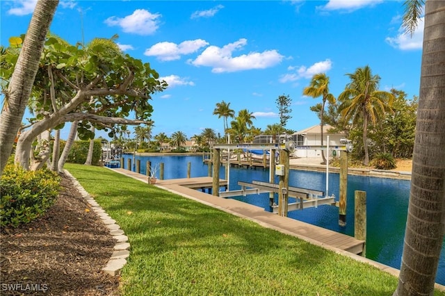 view of dock with a lawn and a water view