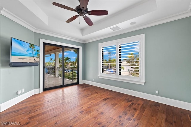 unfurnished room with a tray ceiling, a wealth of natural light, hardwood / wood-style flooring, and ceiling fan