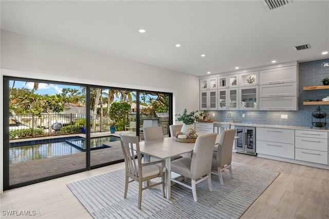 dining area with wine cooler, plenty of natural light, and light wood-type flooring