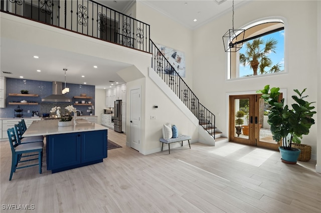 foyer with french doors, crown molding, a notable chandelier, a high ceiling, and light hardwood / wood-style floors