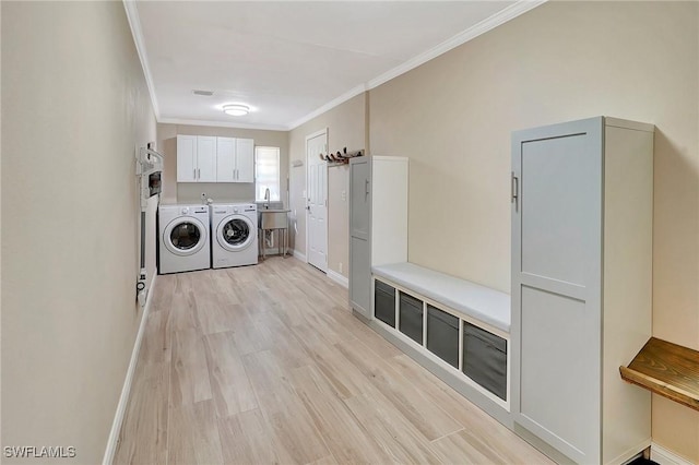 clothes washing area with washer and dryer, cabinets, light wood-type flooring, and ornamental molding