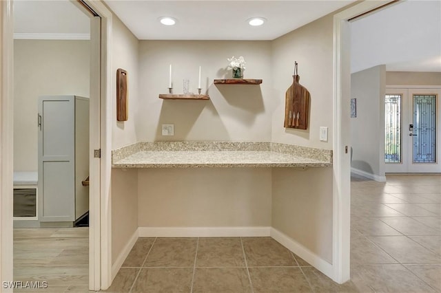 interior space with light stone countertops, light tile patterned floors, and ornamental molding