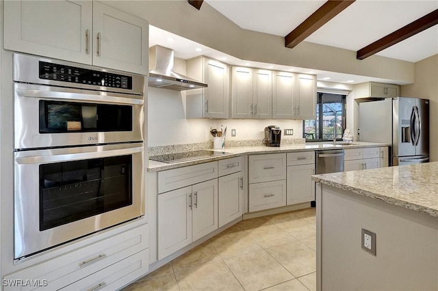 kitchen with wall chimney range hood, sink, appliances with stainless steel finishes, beamed ceiling, and white cabinetry