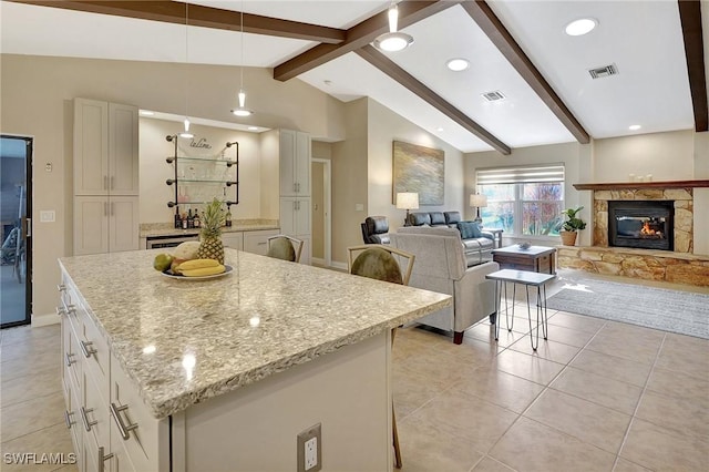 kitchen with white cabinetry, light stone countertops, a kitchen breakfast bar, vaulted ceiling with beams, and pendant lighting