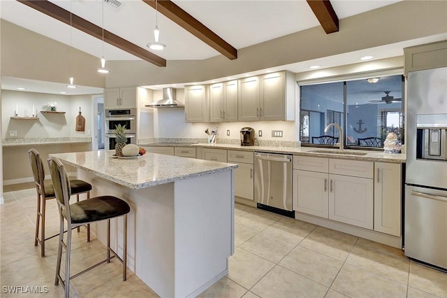 kitchen with wall chimney exhaust hood, stainless steel appliances, sink, beamed ceiling, and a center island