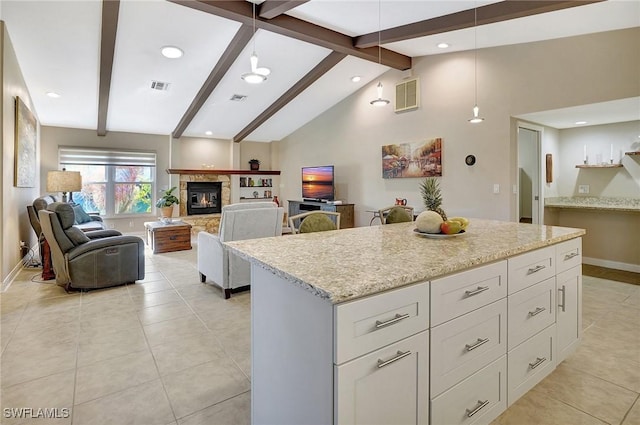 kitchen with white cabinets, a center island, beamed ceiling, and hanging light fixtures