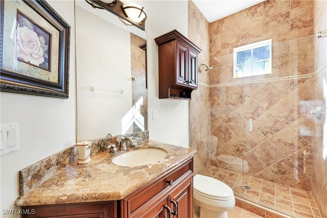 bathroom featuring a tile shower, vanity, and toilet