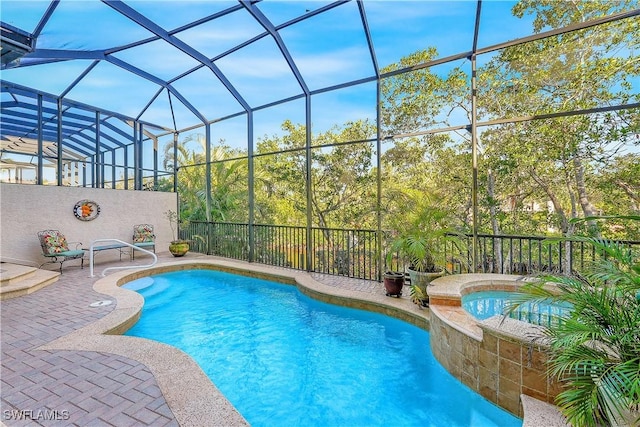 view of pool with a patio area, glass enclosure, and an in ground hot tub