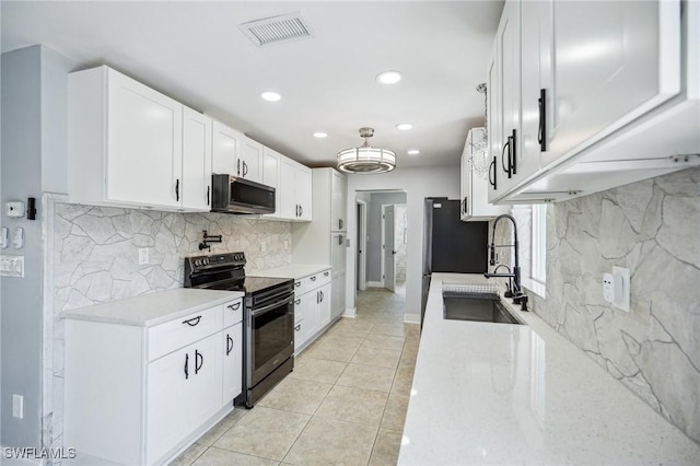 kitchen with sink, light tile patterned floors, black range with electric cooktop, light stone counters, and white cabinets