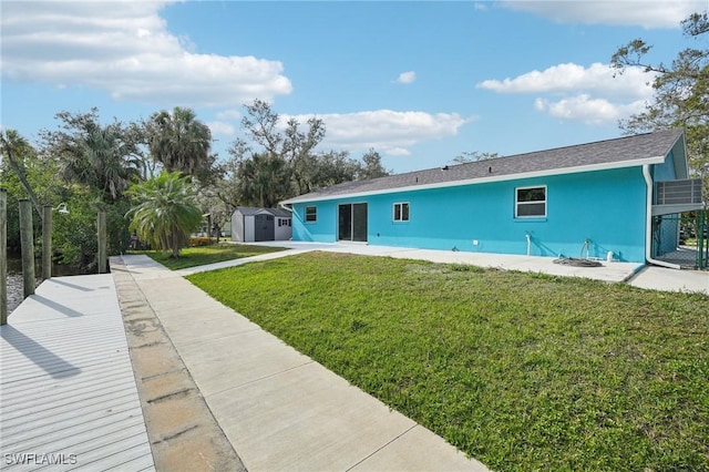 rear view of house featuring a storage unit and a lawn