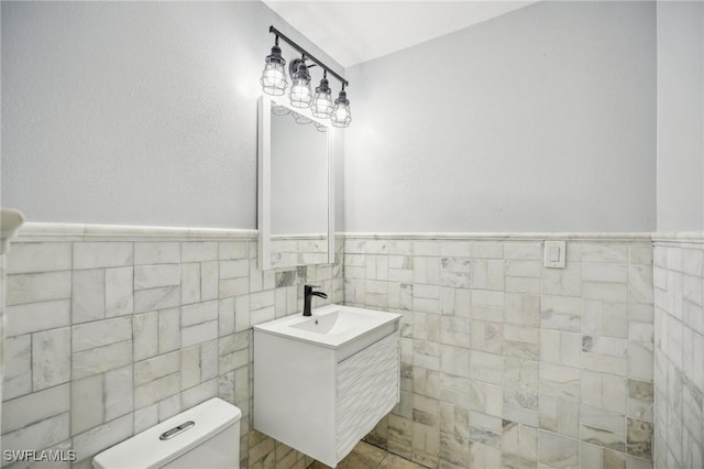 bathroom featuring vanity, tile walls, and toilet