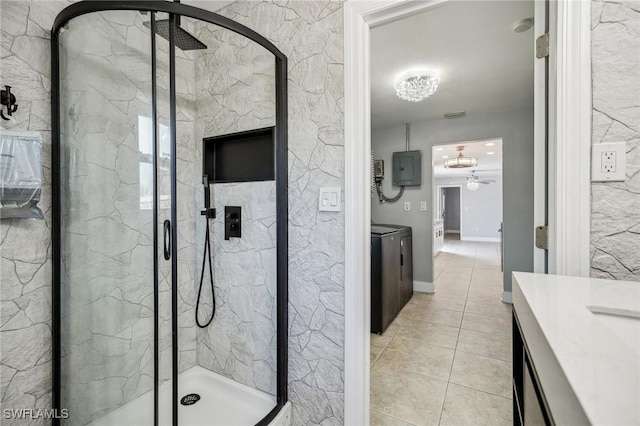 bathroom featuring an enclosed shower, vanity, tile patterned flooring, washing machine and dryer, and electric panel