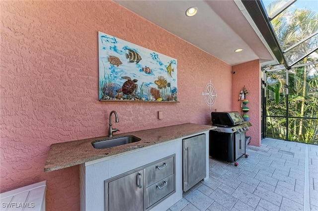 view of patio / terrace featuring an outdoor kitchen, glass enclosure, grilling area, and sink