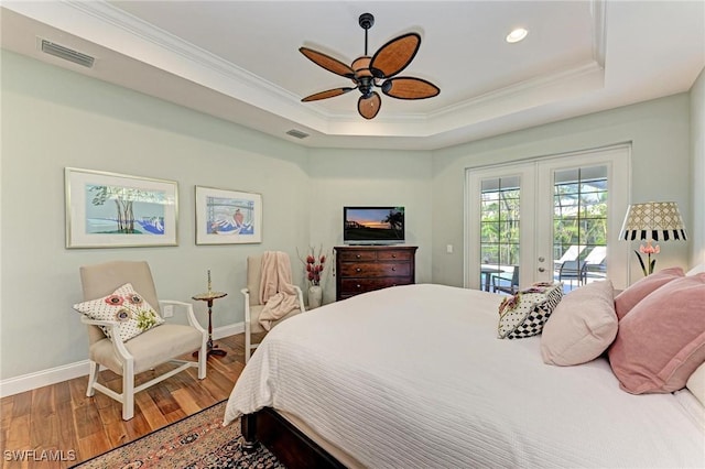 bedroom featuring ceiling fan, french doors, hardwood / wood-style floors, a tray ceiling, and access to outside