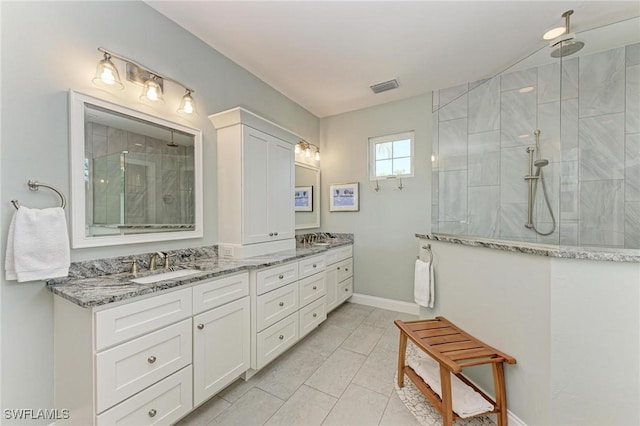 bathroom with tile patterned flooring, vanity, and tiled shower