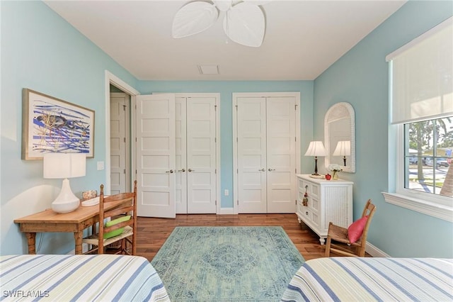 bedroom featuring dark hardwood / wood-style floors, ceiling fan, and multiple closets