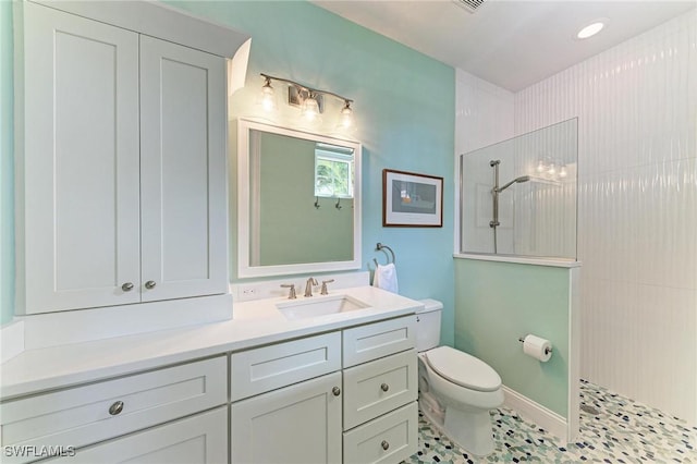 bathroom featuring a tile shower, tile patterned flooring, vanity, and toilet