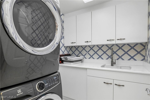 laundry room featuring sink, cabinets, and stacked washer / dryer