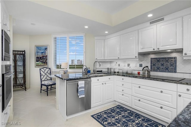 kitchen with white cabinets, appliances with stainless steel finishes, dark stone counters, and sink