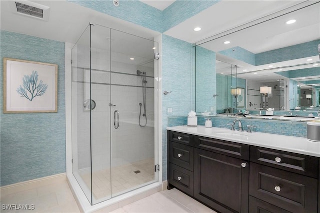 bathroom featuring vanity, a shower with shower door, tile patterned floors, and tasteful backsplash