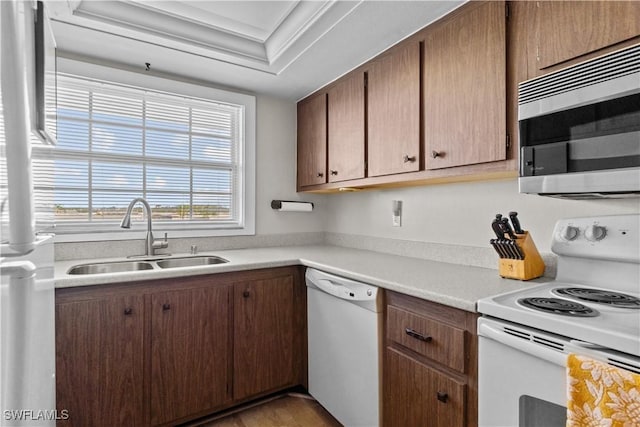 kitchen with white appliances, a tray ceiling, crown molding, and sink