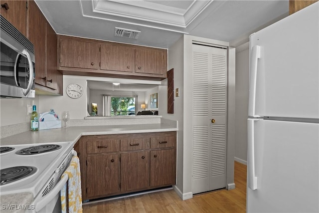 kitchen featuring white appliances, light hardwood / wood-style floors, and ornamental molding