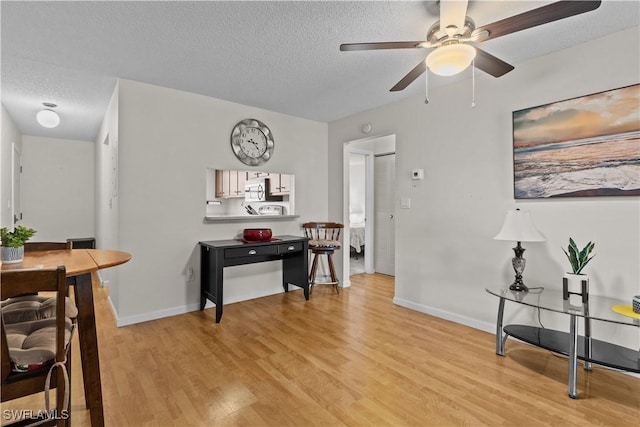 dining space with ceiling fan, light wood-type flooring, and a textured ceiling