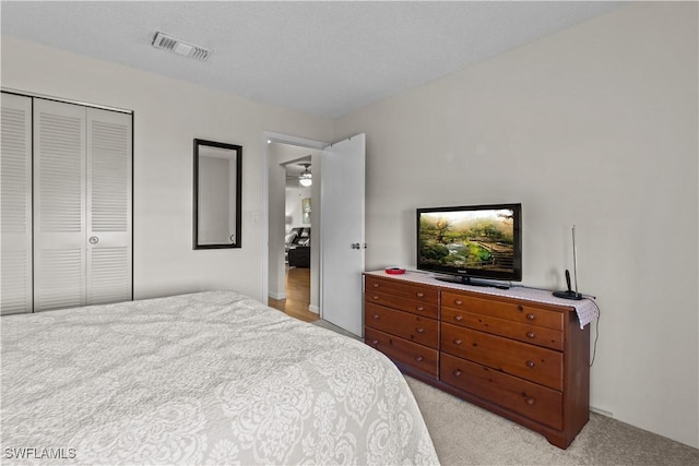 carpeted bedroom with a textured ceiling and a closet