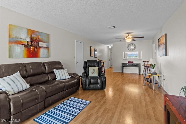 living room featuring a textured ceiling, light hardwood / wood-style flooring, and ceiling fan