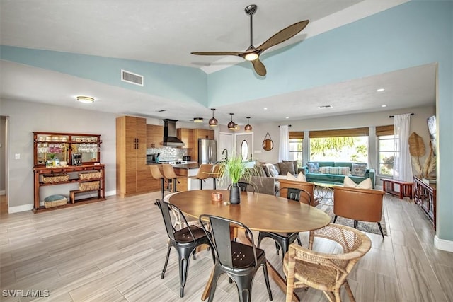 dining room with ceiling fan, light hardwood / wood-style floors, and vaulted ceiling