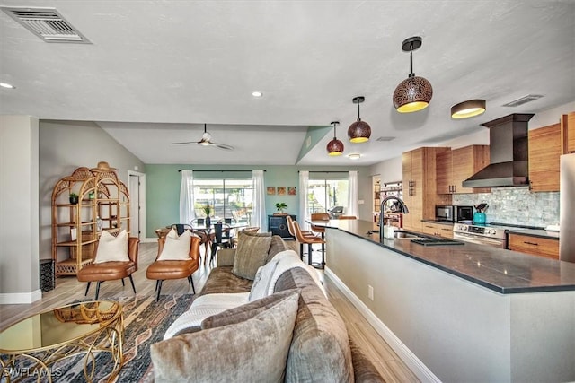 living room with ceiling fan, light wood-type flooring, sink, and lofted ceiling