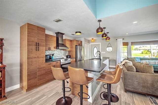 kitchen featuring sink, wall chimney exhaust hood, decorative backsplash, decorative light fixtures, and stainless steel appliances