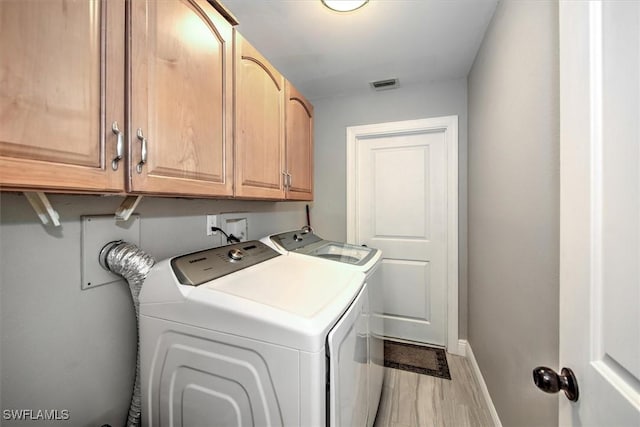 laundry area featuring cabinets, separate washer and dryer, and light hardwood / wood-style flooring