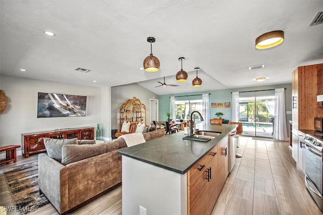 kitchen featuring appliances with stainless steel finishes, ceiling fan, sink, decorative light fixtures, and an island with sink