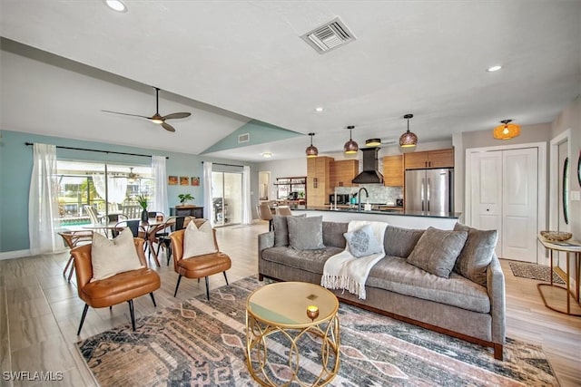 living room featuring ceiling fan, sink, lofted ceiling, and light hardwood / wood-style flooring