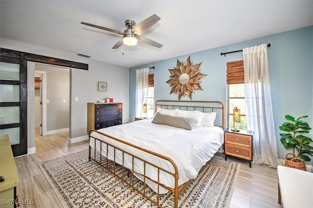 bedroom with multiple windows, light hardwood / wood-style flooring, and ceiling fan